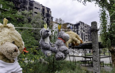juguetes para niños cuelgan de una cuerda en el fondo de casas quemadas destruidas guerra en Ucrania con Rusia