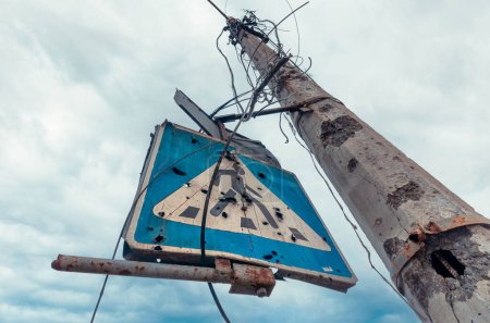 pilar de hormigón roto por fragmentos y señal de tráfico azul contra un cielo sombrío en Mariupol Ucrania