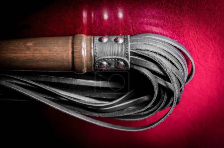Téléchargez les photos : Noir cuir bdsm cils sur un fond rouge - en image libre de droit