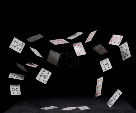 Spielkarten fallen auf schwarzen Tisch auf dunklem Hintergrund