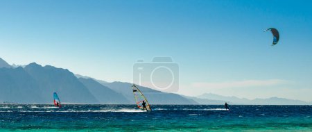 Téléchargez les photos : Planche à voile et kitesurfers balade dans la mer Rouge sur le fond de la côte rocheuse en Egypte Dahab - en image libre de droit