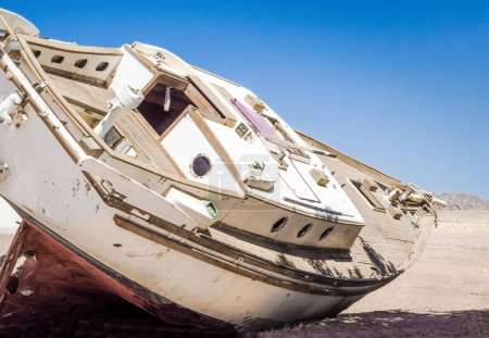 Photo for Old yacht lies on the sand in the desert against the blue sky - Royalty Free Image