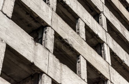 abstraktes Hintergrundfragment eines grauen Betongebäudes mit leeren Fenstern
