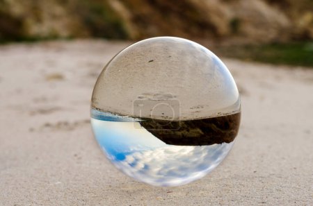 glass crystal ball lens lies on the sand of the sea shore