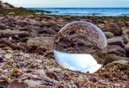glass crystal ball lens lies on the sand of the sea shore landscape