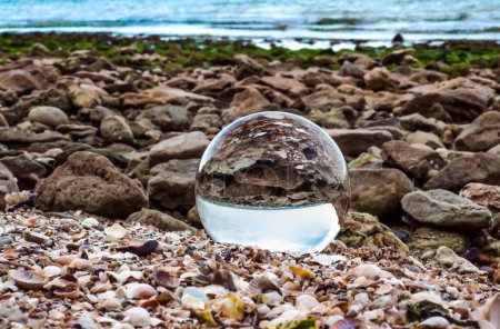 glass crystal ball lens lies on the sand of the sea shore