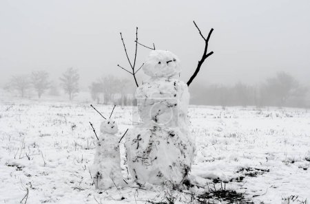 creepy snowmen from dirty snow on the background of trees and fog
