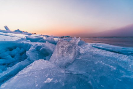 winter seascape with broken ice in the foreground at pink sunset