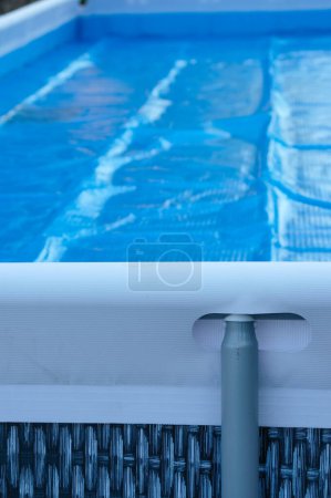 Una piscina rectangular marco. Soporte metálico. Cubierta de piscina. Película solar azul. Copiar espacio.