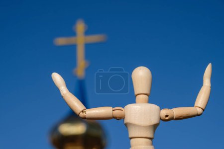 Foto de Una muñeca maniquí de madera con las manos extendidas sobre una iglesia y el fondo del cielo azul. Vista trasera. - Imagen libre de derechos