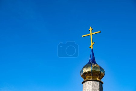 Foto de Cruz de madera y la cúpula dorada de la capilla de la iglesia. Reflexión paisajística. Fondo cielo azul. Copiar espacio. - Imagen libre de derechos