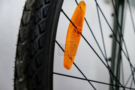 Téléchargez les photos : Bike reflector. A simple orange plastic cataphote on a bicycle wheel. Safe driving in the dark. - en image libre de droit