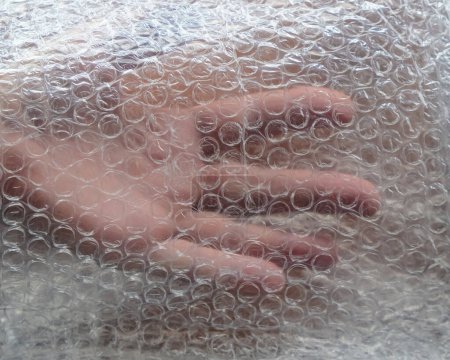 Foto de Mano humana bajo el envoltorio de burbujas de aire. - Imagen libre de derechos