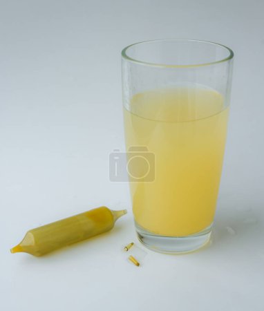 Téléchargez les photos : Mélange de compléments alimentaires et de vitamines dans un verre d'eau. L'ampoule ou la cartouche à double embout. - en image libre de droit