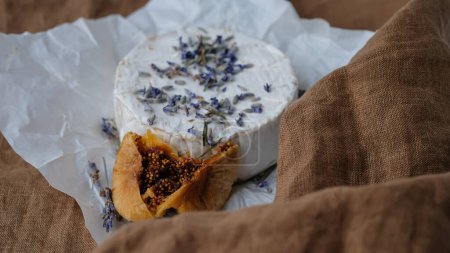 Photo for French Camembert cheese, dry fig, dry lavender. Brown linen tablecloth. Copy space. - Royalty Free Image