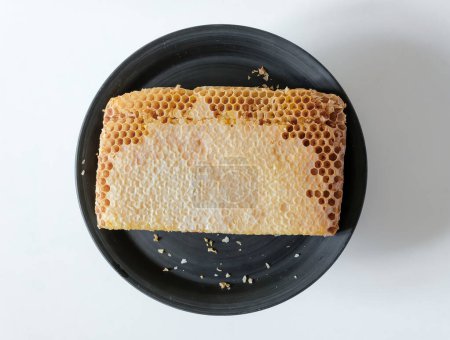 Honeycombs full of honey. Sealed honeycombs. Unfilled edges. Black ceramic plate. 