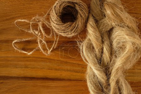 Fibers of natural flax or hemp, tow, and skein. Wooden background. Flax or hemp processing concept. Growing demand for natural fibers. Sustainable resource. Copy space.