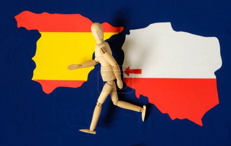 Menschliche Schaufensterpuppen aus Holz laufen. Polen-Karte. Spanien-Karte. Pfeil. Bevölkerungswanderung von Polen nach Spanien. Blauer Hintergrund der Flagge der Europäischen Union.
