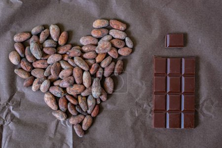 Téléchargez les photos : Des fèves de cacao. Le coeur. Barre chocolatée. Production de chocolat de haricots à barres. Fond brun. - en image libre de droit