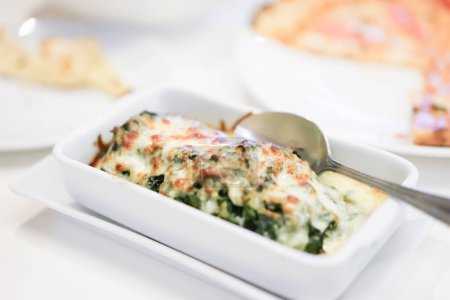 Photo for Baked spinach with cheese is easily made by smothering the spinach in cheese sauce and baking it until golden and bubbly - Royalty Free Image