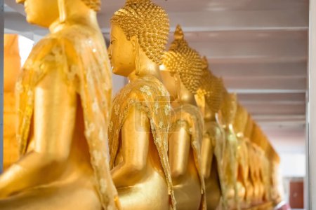 Foto de Una gran cantidad de estatua de oro de Buda sentado meditó en la fila en el templo de Tailandia. - Imagen libre de derechos