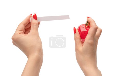 Frauenhand mit roten Nägeln mit Teststreifen für das Parfüm, isoliert auf weißem Hintergrund. Parfümdiebe.