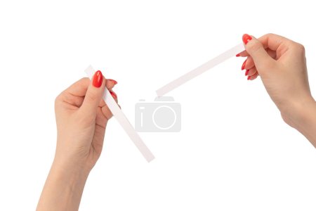 Foto de Mano de mujer con uñas rojas con tiras de prueba para el perfume, aislada sobre un fondo blanco. Bloqueadores de perfume. - Imagen libre de derechos