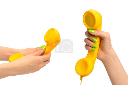 Gelber Hörer in Frauenhand mit grünen Nägeln auf weißem Hintergrund. Kopierraum.