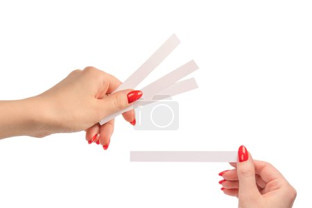 Main de femme avec des ongles rouges avec des bandes d'essai pour le parfum, isolé sur un fond blanc. Boutons de parfum.