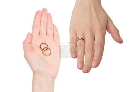 Deux anneaux dorés dans une main de femme isolée sur un fond blanc. Concept de mariage. 