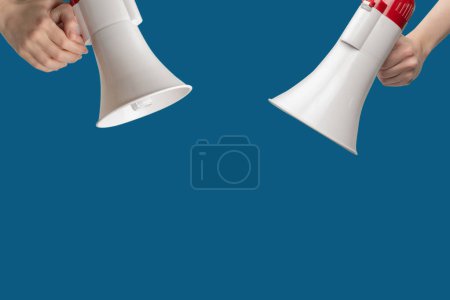 Megaphone in woman hands on a blue background.  Copy space. 