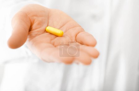 Foto de Modelo femenino en exfoliante blanco sostiene píldora en su mano vista de cerca - Imagen libre de derechos