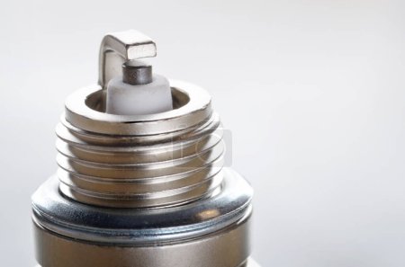 Closeup photo of new spark plug for internal combustion engine on metal background. Space for text