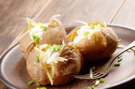 Téléchargez les photos : Pommes de terre cuites au four avec ciboulette, fromage et crème sure - en image libre de droit