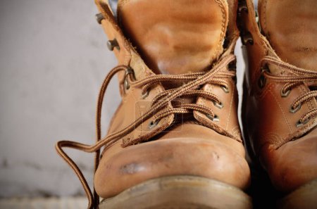 Yellow leather used work boots on concrete background closeup