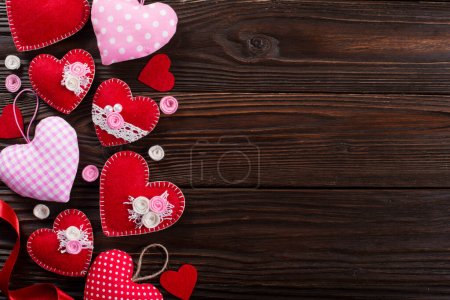 Téléchargez les photos : Sewed handmade fabric hearts for valentine day on dark wooden background with copy space - en image libre de droit