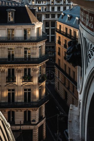 Rooftop view on windows and balconies of an apartment building from Printemps Haussmann in Paris, France. Romantic sunset view with close up detail traditional architecture of residential buildings.