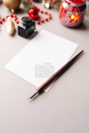 Photo for Set of vintage dip pen, inkpot and blank paper sheet with envelope on white wooden table, Christmas decoration - Royalty Free Image
