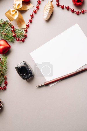 Photo for Set of vintage dip pen, inkpot and blank paper sheet with envelope on white wooden table, Christmas decoration - Royalty Free Image
