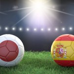 Two soccer balls in flags colors on stadium blurred background. Japan vs Spain. 3d image