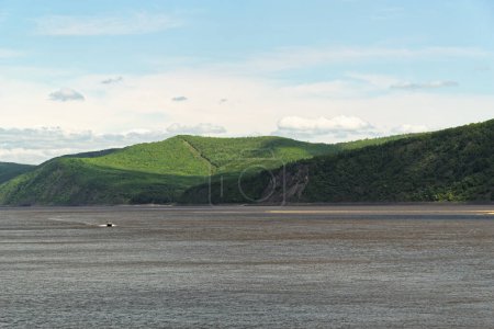 Photo for Motorboat on Amur river against forested hills and blue sky, Komsomolsk-on-Amur, Russia - Royalty Free Image