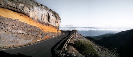 Téléchargez les photos : Panorama de route de montagne courbée dangereuse avec espace texte au-dessus des nuages - en image libre de droit
