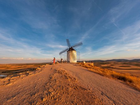 Téléchargez les photos : Vue grand angle de l'ancien moulin à vent au coucher du soleil avec des touristes flous - en image libre de droit