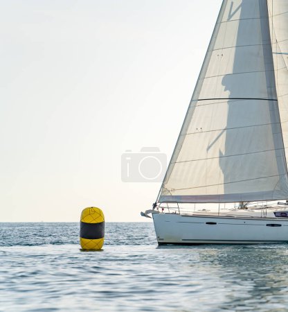 Téléchargez les photos : Sailboat bow arrives at buoy under clear white sky for text - en image libre de droit