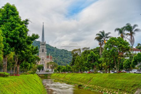 Long exposure shot of Petropolis Cathedral with flowing river and silky water. Abstract sky with clouds and motion blur convey the passage of time.