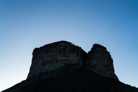 Photo for The silhouette of a cross on Father Ignacios Morro in Chapada Diamantina is visible against a clear blue dusk sky, with space for text. - Royalty Free Image
