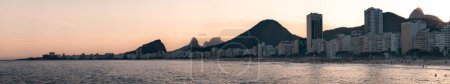 Foto de Crepúsculo desciende en la playa de Copacabana, con un horizonte moderno y el perfil icónico de Cristo Redentor en Río. - Imagen libre de derechos
