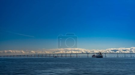 Foto de Puente Niteroi une ciudades mientras buques portacontenedores pasan por debajo, destacando hazañas de ingeniería. - Imagen libre de derechos