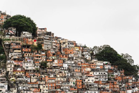 Téléchargez les photos : Une favela animée à flanc de colline avec des maisons colorées met en évidence la forte disparité entre la pauvreté locale et la richesse urbaine environnante. - en image libre de droit