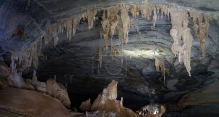 Téléchargez les photos : Les touristes anonymes explorent une grande grotte, éclairée par des lanternes portatives qui mettent en évidence ses caractéristiques géologiques. - en image libre de droit